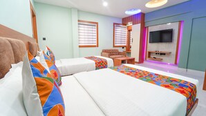 Une chambre d’hôtel avec deux lits, une télévision et un petit coin salon.