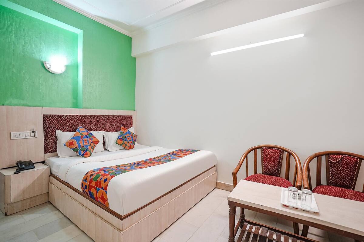 A hotel room with a bed, bedside table, and a small dining table with chairs.