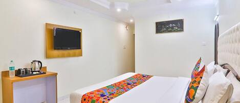 A hotel room with a bed, a desk, a television, and a ceiling fan.