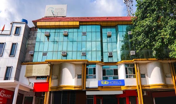A hotel with a blue facade, multiple air conditioning units, and a sign for 'fabHOTELS'.