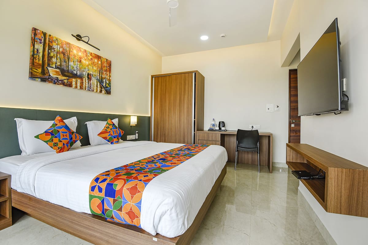 A hotel room with a bed, a desk, a TV, and a wardrobe.