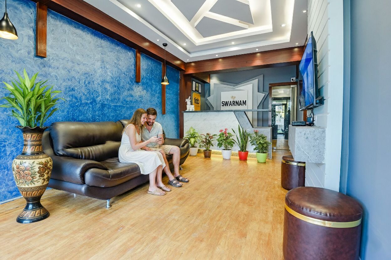 Un espace d’accueil avec un mur bleu à texture, un canapé en cuir et une enseigne sur laquelle on peut lire « SWARNAM ».