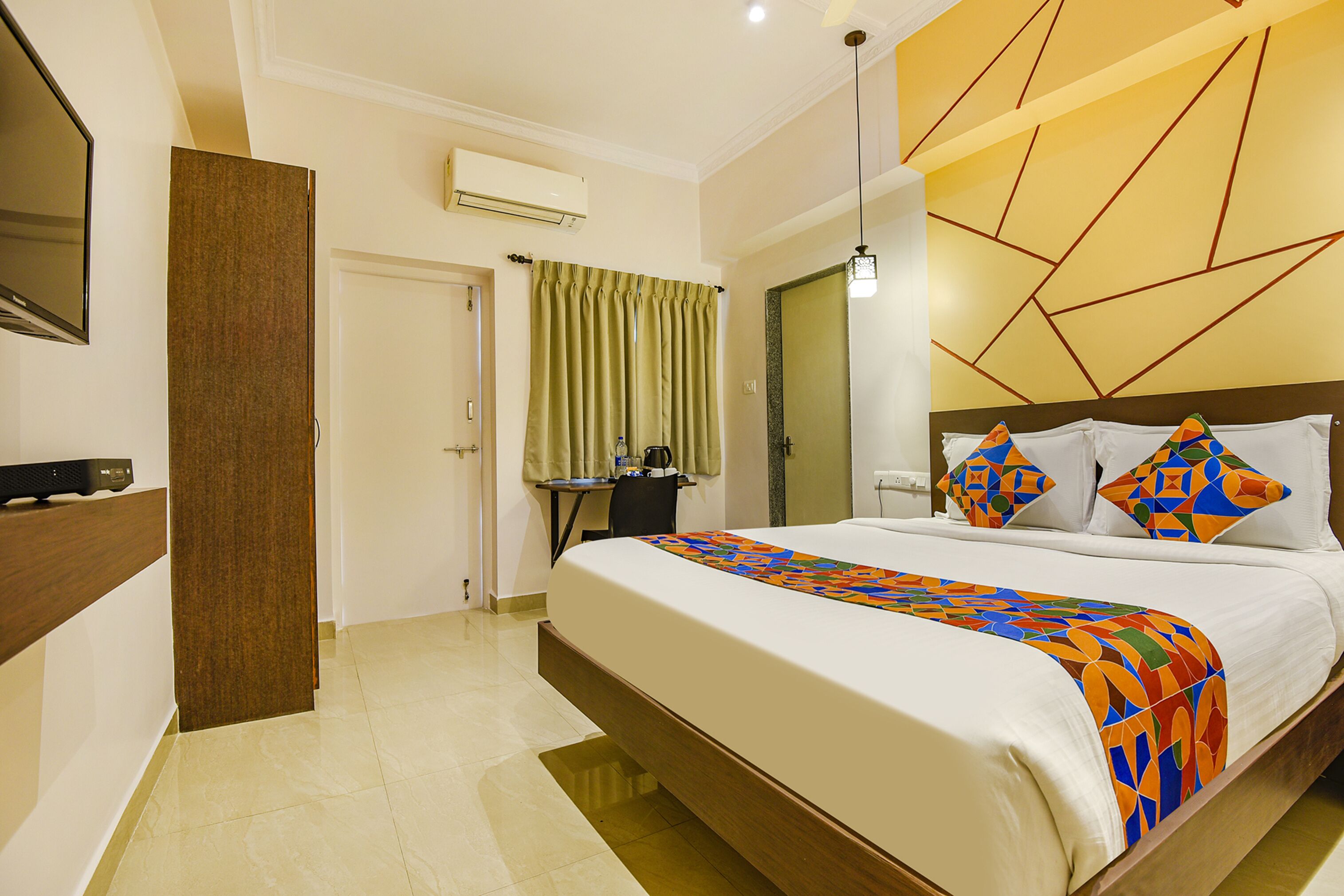 A hotel room with a large bed, a desk, and a mirror.