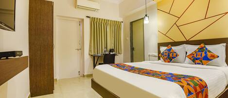 A hotel room with a large bed, a desk, and a mirror.