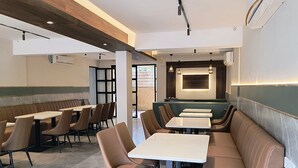 Interior moderno de restaurante com assentos em cabines, mesas altas e iluminação pendente.