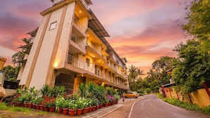 Hotel com vários andares, varandas e área de jardim com plantas em vasos.