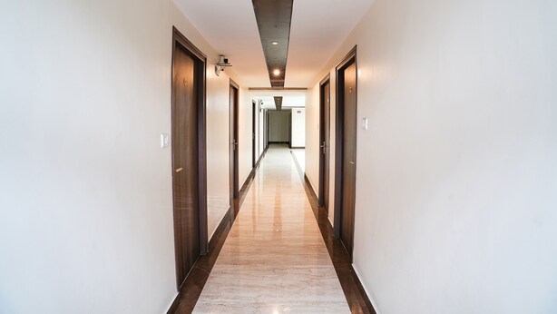 Un pasillo largo y estrecho con puertas de madera a ambos lados y suelo pulido.