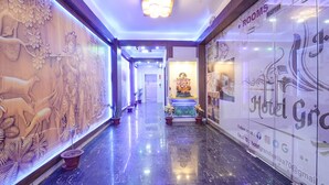 A hotel corridor with a reception area, a statue, and potted plants. - Fabhotel Keptown (Danapur)