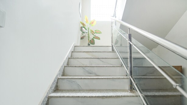 A marble staircase with glass railings leading to a landing. - Fabhotel Keptown (Danapur)
