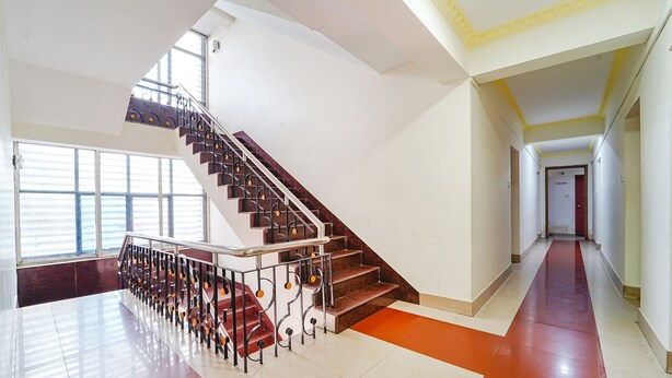 A spacious interior with a grand staircase, large windows, and a long hallway. - Fabexpress Majestic Inn (Thiruvananthapuram)