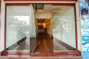A hotel entrance with a glass door, a tiled floor, and a visible hallway leading inside. - Fabexpress Majestic Inn (Thiruvananthapuram)