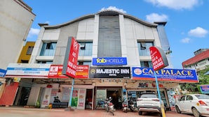 A hotel with a prominent sign for Majestic Inn, adjacent to a building with a sign for Fab Hotels. - Fabexpress Majestic Inn (Thiruvananthapuram)