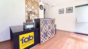 A reception desk with a logo, a wooden decorative partition, and a clock. - Fabhotel Qube (Kanayannur)
