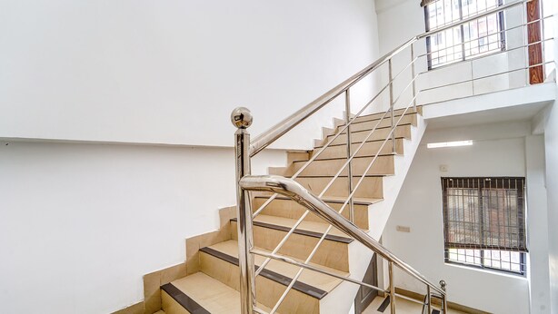 A modern staircase with metal railings and wooden steps, leading to an upper floor. - Fabhotel Qube (Kanayannur)