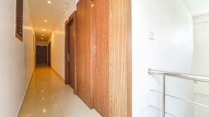 A hallway with a wooden door, a metal handrail, and a tiled floor. - Fabhotel Qube (Kanayannur)