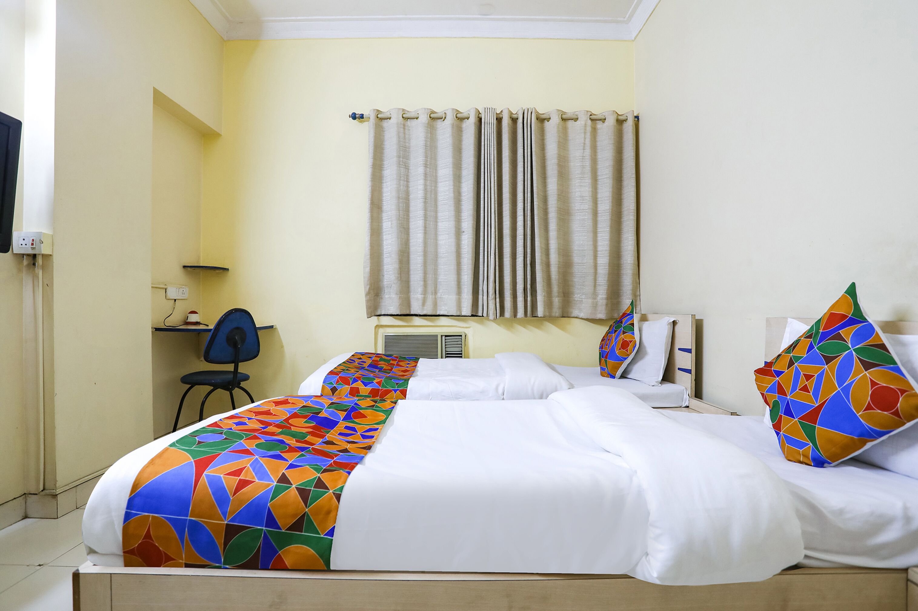 A hotel room with two beds, a desk, and a chair.
