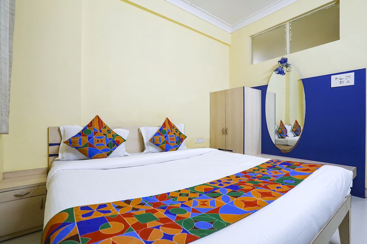 A hotel room with a large bed, a mirror, a wardrobe, and a nightstand.