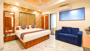 A modern bedroom with a large bed, a blue sofa, and a ceiling fan. - Fabhotel Prime Kharadi Residency (Pune)