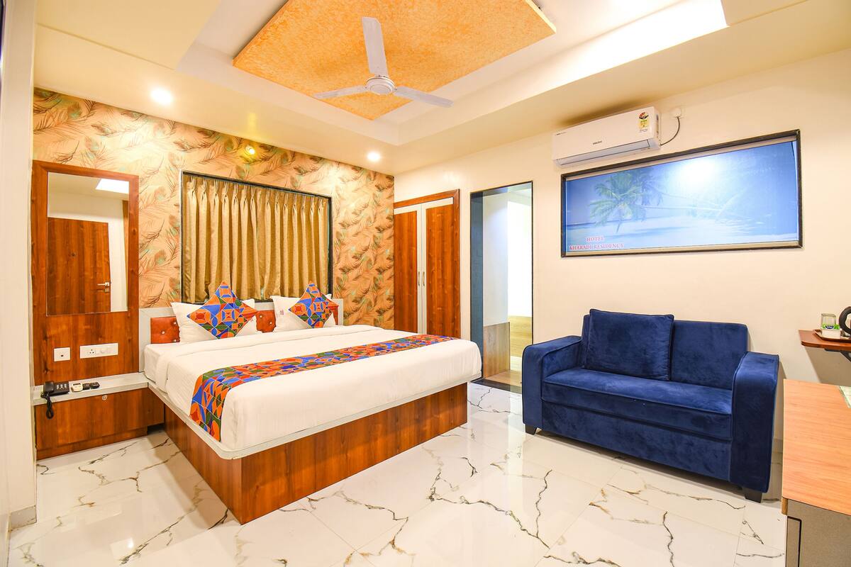 A modern bedroom with a large bed, a blue sofa, and a ceiling fan.