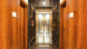 A wooden elevator with marble walls and a metal door. - Fabhotel Prime Kharadi Residency (Pune)