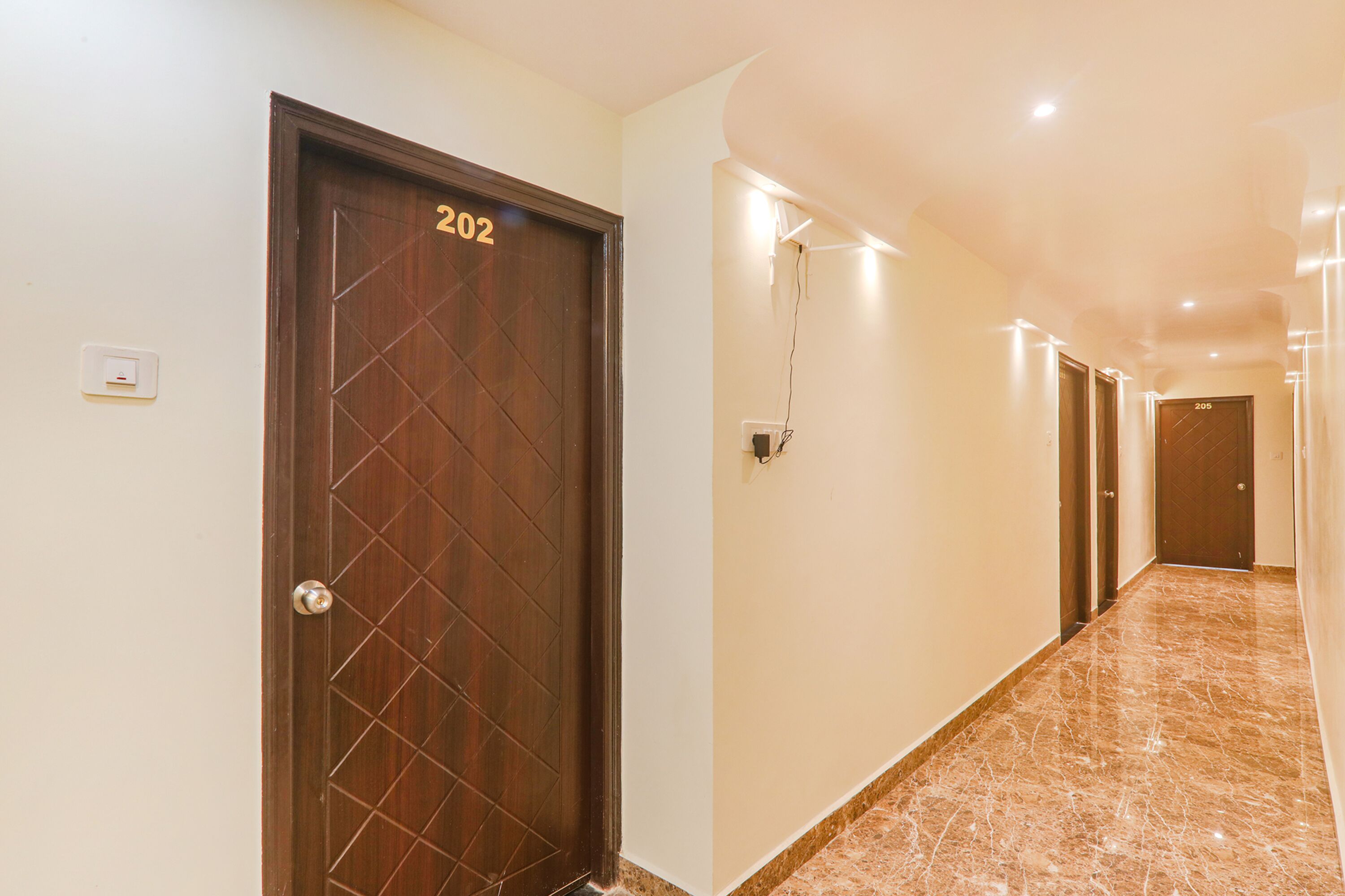 A hallway with a wooden door labeled "202" and a marble floor.