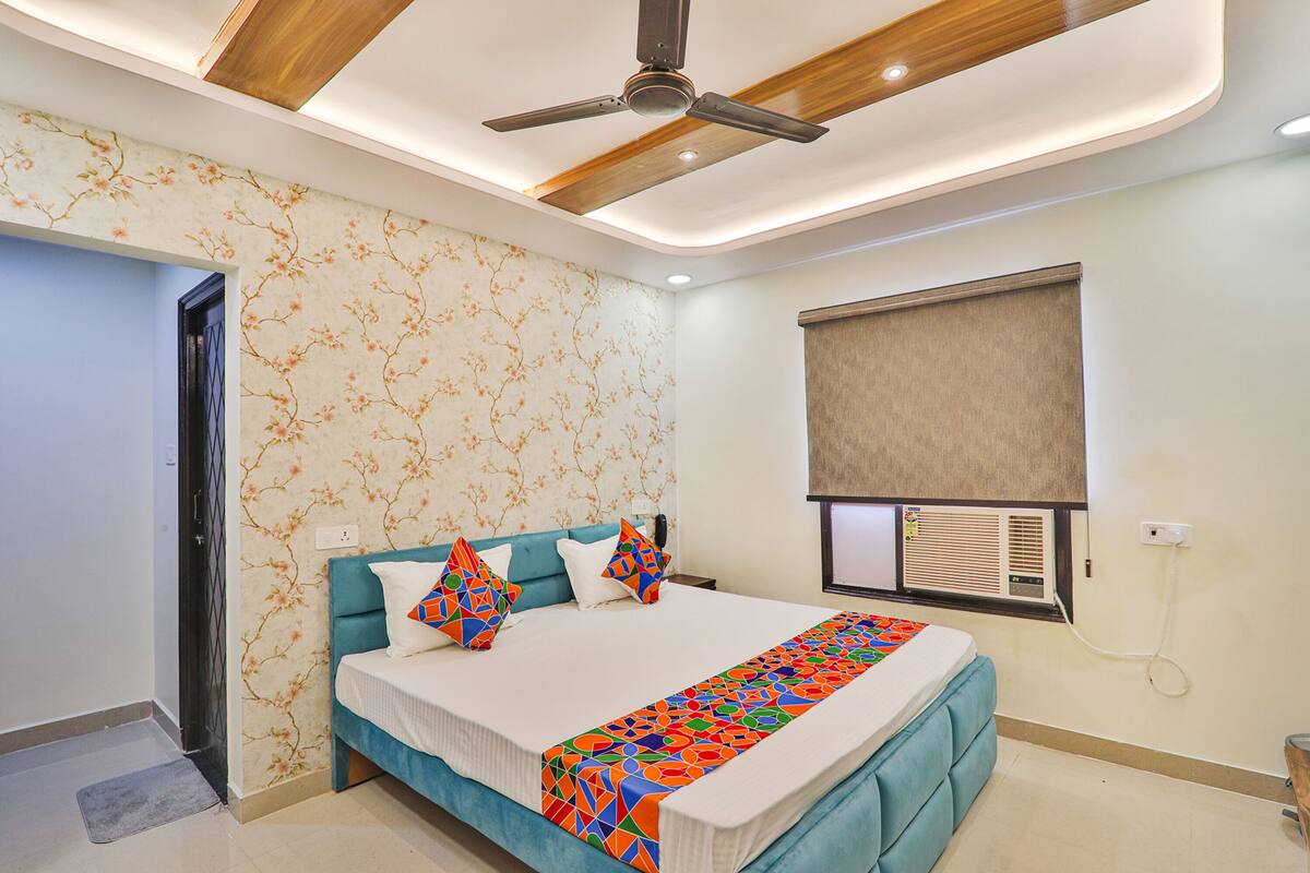 A bedroom with a bed, a ceiling fan, a window with blinds, and a wall-mounted air conditioner.
