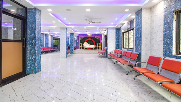 A spacious lobby with a marble floor, rows of red chairs, and a central area with a decorative backdrop. - Fabhotel Santoshi (Kolkata)