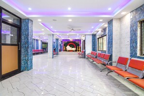 Un hall d’entrée spacieux, doté d’un sol en marbre, de rangées de chaises rouges et d’un espace central agrémenté d’un décor.