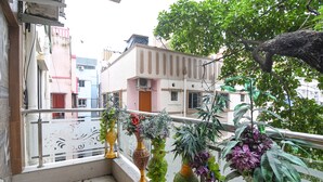 A balcony with potted plants, a view of neighboring buildings, and a tree. - Fabhotel Santoshi (Kolkata)