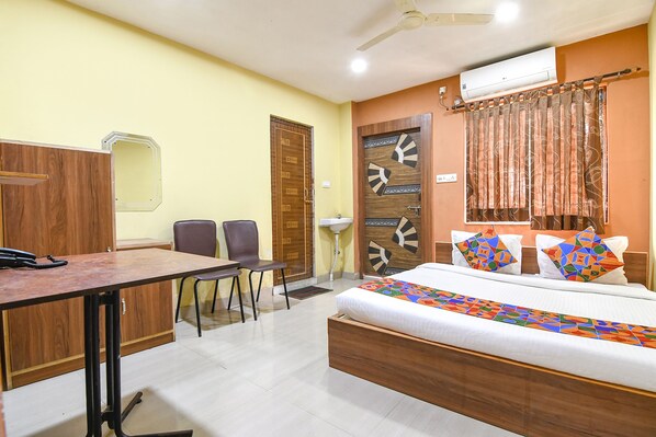 Une chambre d’hôtel comprenant un lit, un bureau, deux chaises, une armoire et une salle de bain.