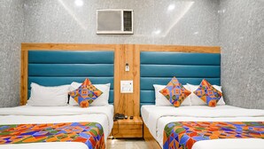 A hotel room with two beds, each with a wooden headboard and a colorful geometric-patterned bedspread. - Fabhotel National (Mumbai)