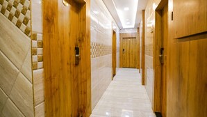 A hallway with wooden doors and tiled walls. - Fabhotel National (Mumbai)