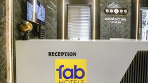 A reception desk with a 'fab hotels' logo, a digital clock, and a 'check out time' sign. - Fabhotel National (Mumbai)
