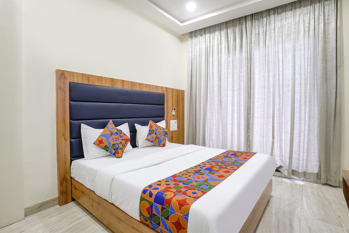 A neatly made bed with a wooden headboard, white bedding, and colorful pillows.