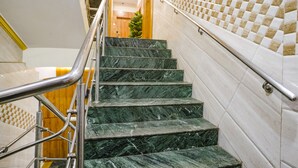 A staircase with marble steps and metal handrails, leading to a room with a checkered tile wall. - Fabhotel National (Mumbai)