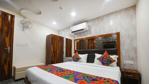Una habitación de hotel con cama, un armario de madera, una mesita de noche pequeña y un equipo de aire acondicionado en la pared.