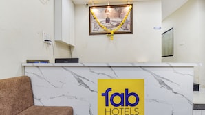 A hotel reception desk with a marble top, a brown sofa, and a 'fab hotels' logo. - Fabexpress Devani Palace (Ujjain)