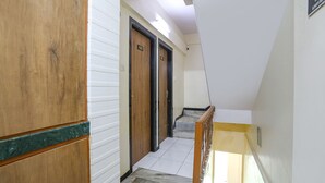 A narrow hallway with wooden doors and a tiled floor, leading to a staircase. - FabHotel Aksa Inn (Mumbai)