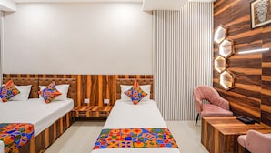 Ett hotellrum med två sängar, en sänggavel i trä, ett skrivbord, en stol och en dekorativ väggpanel.
