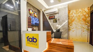 En hotellobby med en receptionsdisk, en digital skärm och en väggmonterad luftkonditioneringsenhet.