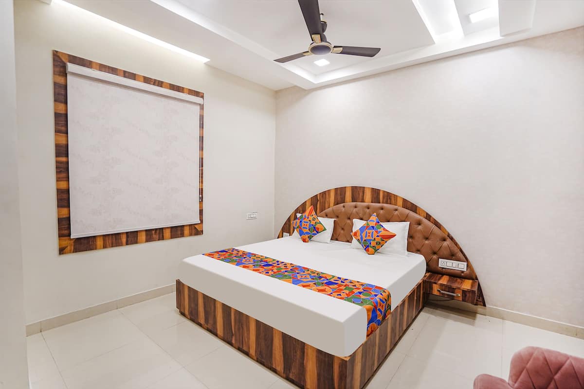 A bedroom with a wooden headboard, a bed with a colorful bedspread, a ceiling fan, and a large window.