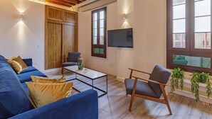 Un salon moderne avec un canapé bleu, un plafond en bois et un téléviseur fixé au mur.