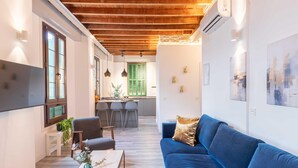Un salon moderne avec un canapé bleu, une table basse surmontée d’un vase et un plafond en bois.