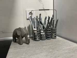 Een bureau met een sculptuur van een geometrische olifant, een stopcontact en een metalen rek met pennen.