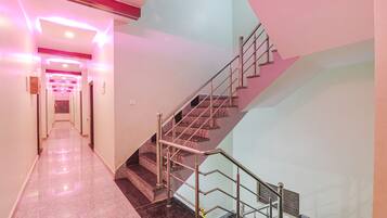 A modern hotel corridor with a staircase and a polished marble floor.