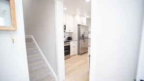 A modern kitchen with white cabinets, stainless steel appliances, and a wooden staircase. - Dayton Diamond- Sleeps 10, Peaceful setting, Game room, Chef's kitchen! (Dayton)