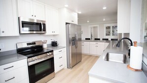 A modern kitchen with white cabinetry, stainless steel appliances, and a central island with a sink. - Dayton Diamond- Sleeps 10, Peaceful setting, Game room, Chef's kitchen! (Dayton)