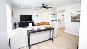 A modern living room with a sofa, a black coffee table, and a television. - Dayton Diamond- Sleeps 10, Peaceful setting, Game room, Chef's kitchen! (Dayton)