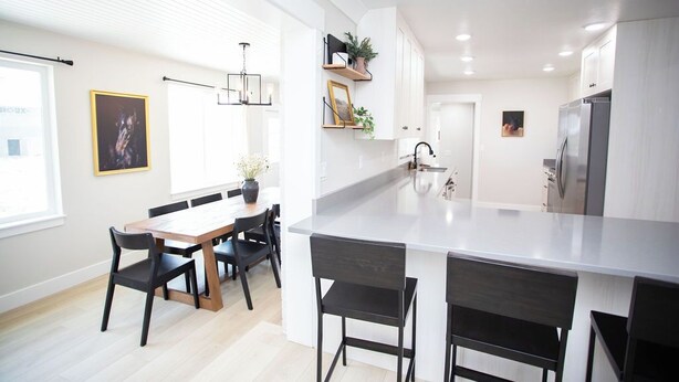 A modern kitchen with a central island, black chairs, a dining table, and white cabinetry. - Dayton Diamond- Sleeps 10, Peaceful setting, Game room, Chef's kitchen! (Dayton)