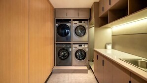 A compact kitchen with built-in appliances, a sink, and wooden cabinets. - Manju Hotel (Shaoxing)